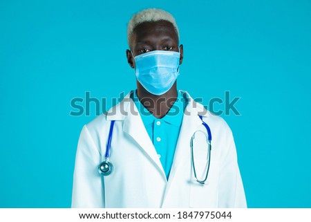 Portrait of african doctor in professional medical coat and mask. Doc man isolated on blue background.