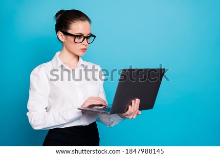 Portrait of nice attractive skilled focused busy specialist holding in hands laptop typing isolated over bright blue color background