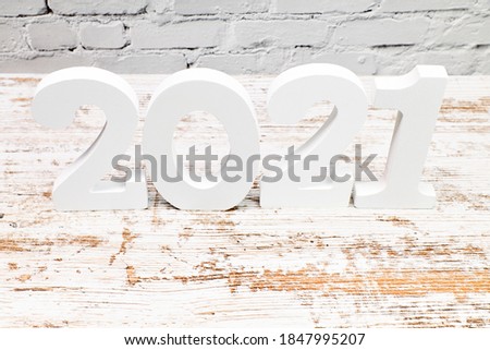 Number 2021 on a board with a white brick background. Happy New Year concept