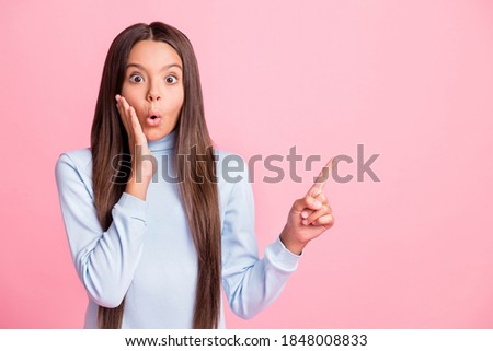 Portrait of school girl shocked hand on cheek indicate finger empty space isolated on pink color background