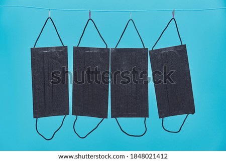 four black medical masks are dried on a clothesline. reusable protective face masks. blue background. copy space