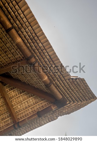 the detail of roof eave using bamboo shingles and big yellow bamboo structure with palm fiber straps base on architectural design enhance the facade aesthetic of the commercial building 