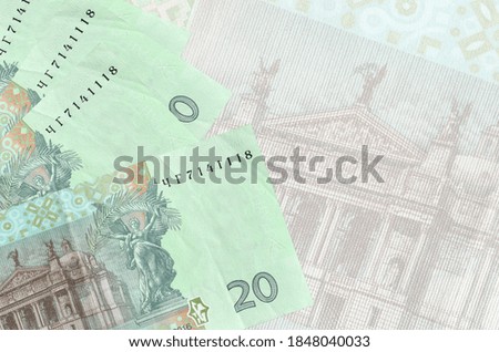 20 Ukrainian hryvnias bills lies in stack on background of big semi-transparent banknote. Abstract business background