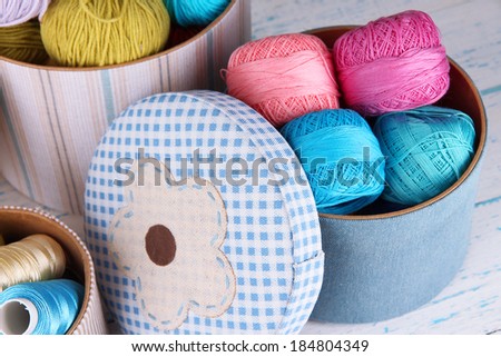 Decorative boxes with colorful skeins of thread on wooden background