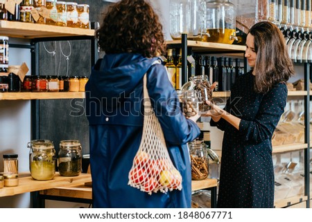 Shop assistant helping customer in bulk food store. Seller advising woman in her purchase of groceries without plastic packaging in zero waste shop. Sustainable shopping at small local businesses. Royalty-Free Stock Photo #1848067771