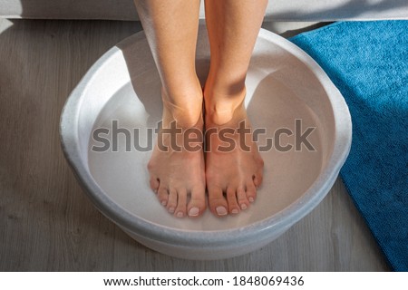 Woman made bath with hot water and baking soda for his feet. Homemade bath soak for dry feet skin Royalty-Free Stock Photo #1848069436