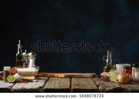 Workplace for cooking. Rustic wooden table with chopped board and ingredients for preparing traditional indian curry. Dark blue background. Food concept.
