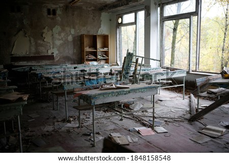 A destroyed school classroom with broken windows in the city of Pripyat, where the nuclear power plant accident occurred in 1986. Image noise. Shallow depth of field.