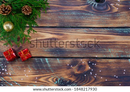 Christmas, winter background - fir branches with balls and gifts on a dark wooden background. Christmas card