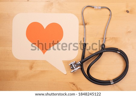 A stethoscope and medical heart disease care icon on a wooden surface