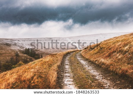 Amazing scene on autumn mountains. Orange grass, first snow and rural road in fantastic morning sunlight. Landscape photography