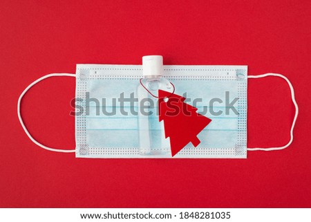 Christmas modern 2021 gift concept. Top above overhead close up flat lay photo picture of face filter respirator and hand antiseptic with small greeting card in shape of tree isolated color background