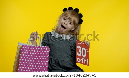 Child girl showing Up To 30 percent Off inscription sign and shopping bags. Teen pupil smiling, looking satisfied with low prices, shopping on Black Friday, Christmas or New Year