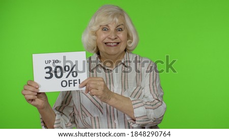 Happy grandmother showing Up To 30 percent Off inscription signs, rejoicing good discounts, low prices for online shopping sales. Black Friday concept. Senior woman isolated on chroma key background