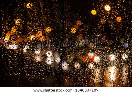 Raindrops on the glass on the background of the road with cars.