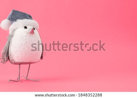 A closeup of a cute penguin toy with a Christmas hat isolated on a pink background