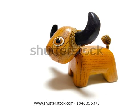A little buffalo doll made of wood carved on a white background.