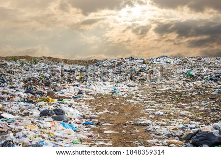 garbage dump pile in trash dump or landfill,backhoe and truck is dumping the gabage from municipal,garbage dump pile and dark sky background  ,pollution concept Royalty-Free Stock Photo #1848359314