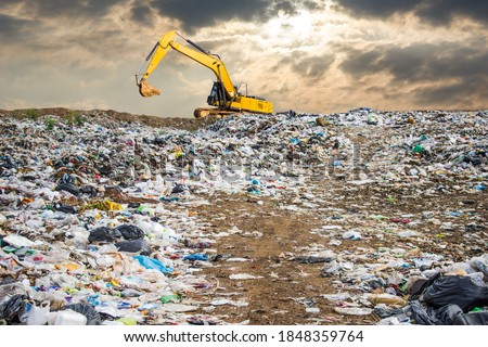 garbage dump pile in trash dump or landfill,backhoe and truck is dumping the gabage from municipal,garbage dump pile and dark sky background  ,pollution concept Royalty-Free Stock Photo #1848359764