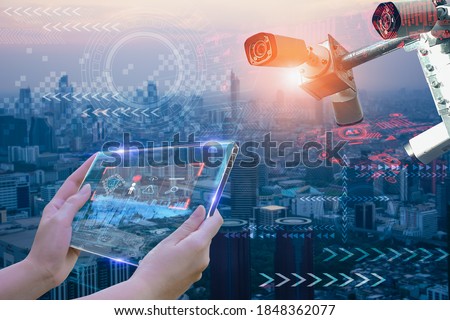Woman hand holding futuristic tablet device,to monitor safety and memorize people's information and behavior in city,concept cctv camera intelligent of artificial intelligence in urban for safety