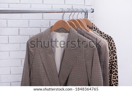 Striped suit and leopard pattern long sleeve shirt with 
knitwear .sweater warm cloth on hangers-wall bakground

