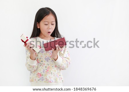 Excited little asian kid girl while open gift box on white background. Happy new year and Merry christmas concept