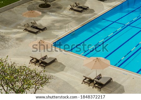 Swimming pool blue water in summer and white beach beds and top view angle.