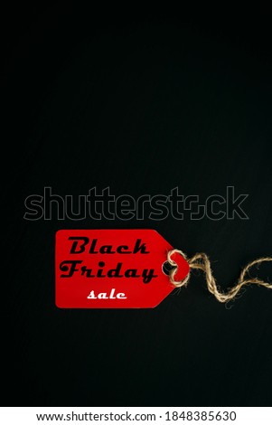 Black friday shopping sale concept. Text on red tag on black wooden background. Vertical image, copy space.
