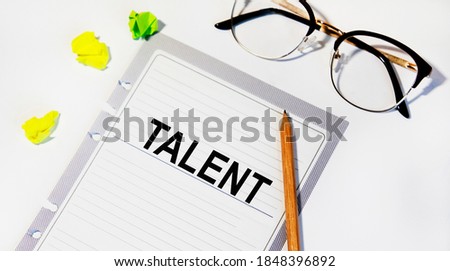 On a sheet from the diary text TALENT, next to a pencil, glasses.