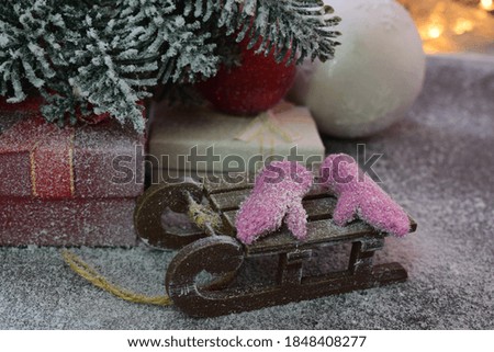 
knitted mittens lie on a wooden sled under the New Year tree