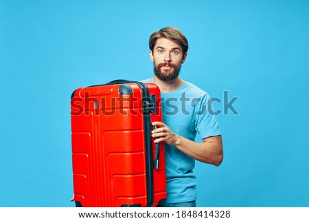Traveler with a red suitcase blue t-shirt isolated background mustache 