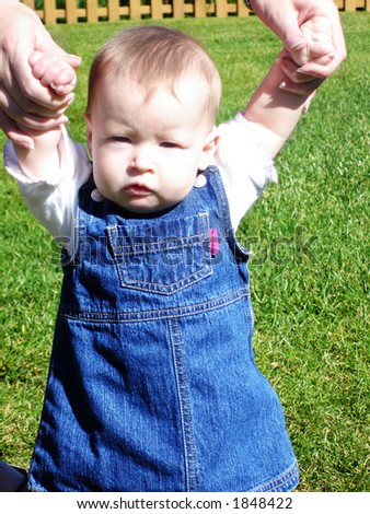 Little Baby Girl in jean dress learning to walk