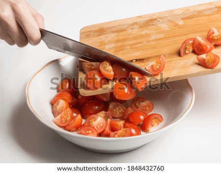 chopped cherry tomatoes are transferred to a salad bowl