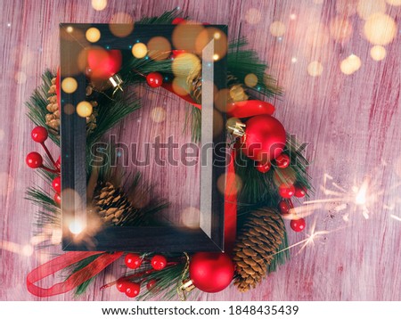 black wooden design frame and Christmas wreath next to it, new year concept on wooden old background.