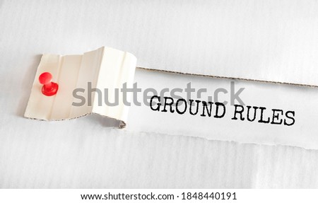 The text GROUND RULES appearing behind torn yellow paper