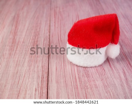 small Santa Claus hat on a wooden background, symbol of Christmas, minimalism.