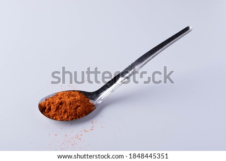 Cayenne pepper in a spoon on a white background