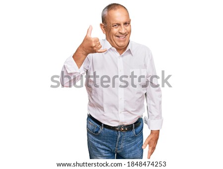 Handsome senior man wearing elegant white shirt smiling doing phone gesture with hand and fingers like talking on the telephone. communicating concepts. 