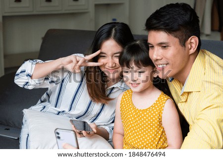 Asian family taking selfie with smartphone at living room.