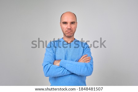 Casual handsome man smiling at camera, hands in pocket.
