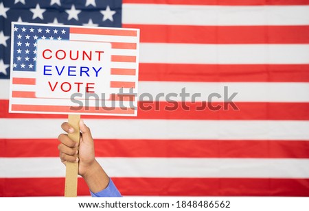 Hands Holding Count every vote sign board with US Flag as Background with copy space - Concept of voter rights and US election