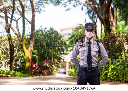 Asian security guard make saluting entry entrance the village. Security Guard Talking a portable wireless transceiver guard entrance to the village door. Speed limit in area, copy space. Royalty-Free Stock Photo #1848491764