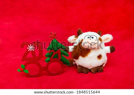 soft toy cows symbol of the new year 2021 and glasses with numbers on a red background
