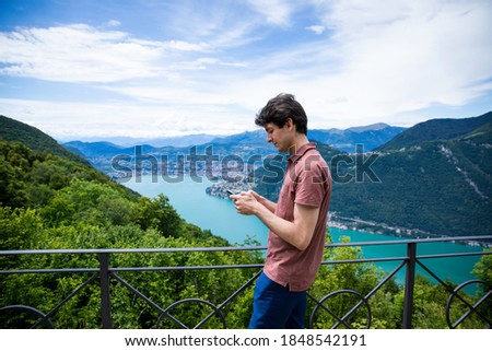 man use phone in a beautiful view of Lugano and it's lake from the Belvedere