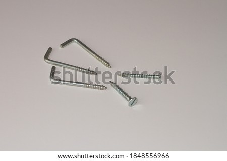 Wall anchoring screws with right angle hooks with zinc coating on white background.