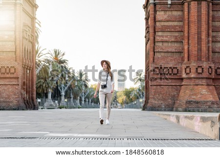 Tourist woman with a camera outdoors. Female solo traveler walking in the streets of barcelona wearing a fedora hat. Traveler outfit. Traveling in Spain and Europe