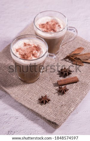 Glass cups with Indian tea masala tea with milk and spices on a napkin, close-up. Copy space