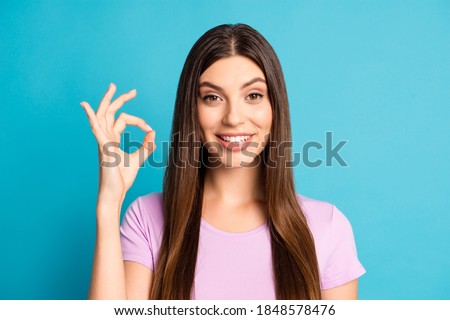 Photo portrait of adorable cute young woman wear casual violet t-shirt showing okey one arm isolated blue color background