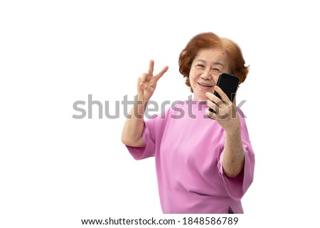 Grandma took a selfie picture with a mobile phone and posing with v-sign fingers. Isolated on white background