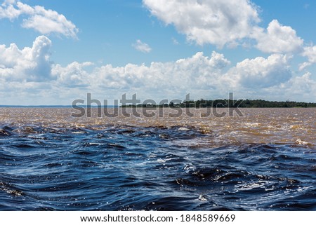 The Meeting of Waters (Encontro das Águas) as the Rio Negro & the Amazon River both mix together, referred to as the Solimões River, near Manaus in the State of Amazonas, Brazil, South America